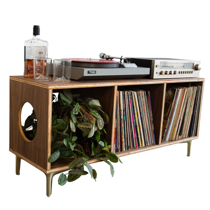 Wooden record player console with vinyl records and a plant on a white background
