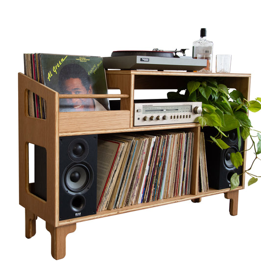 Wooden record player console with records, speakers, and a plant on a white background