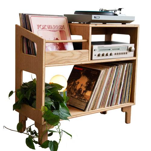 Wooden record player console with vinyl records and a plant on a white background