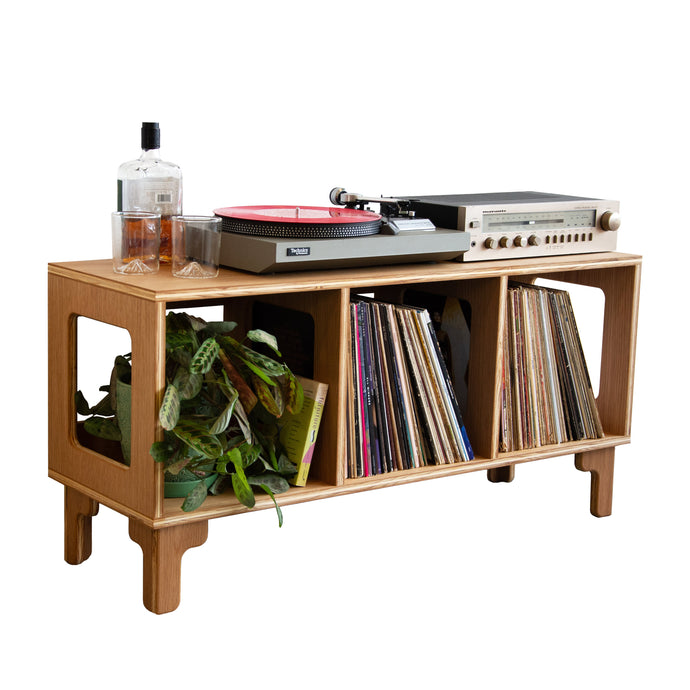 Wooden record player console with vinyl records and a bottle on a white background