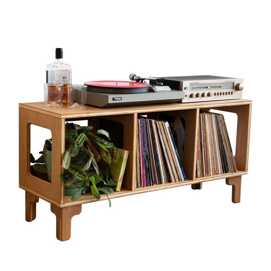 Wooden record player console with vinyl records and a bottle on a white background