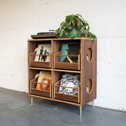 Wooden turntable stand with decorative items against a white brick wall.