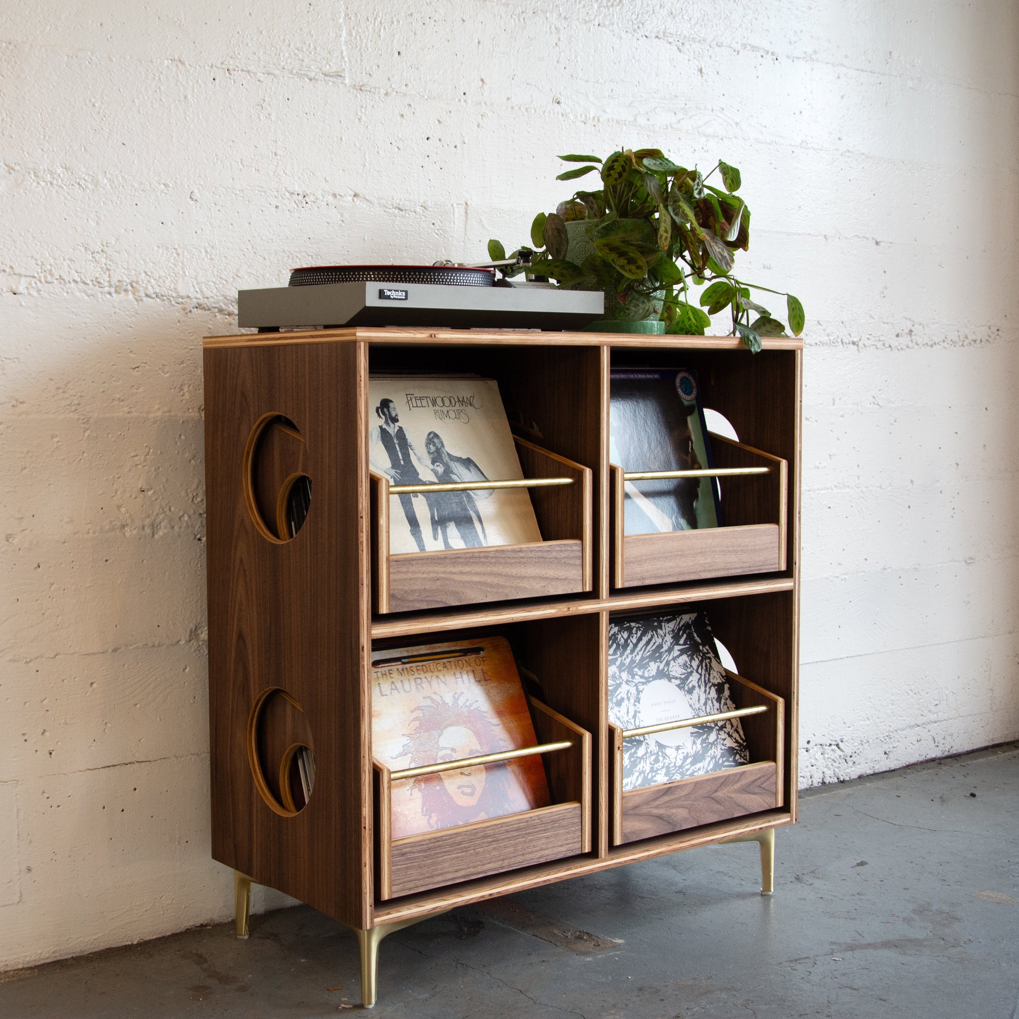Wooden record cabinet with decorative items against a white brick wall