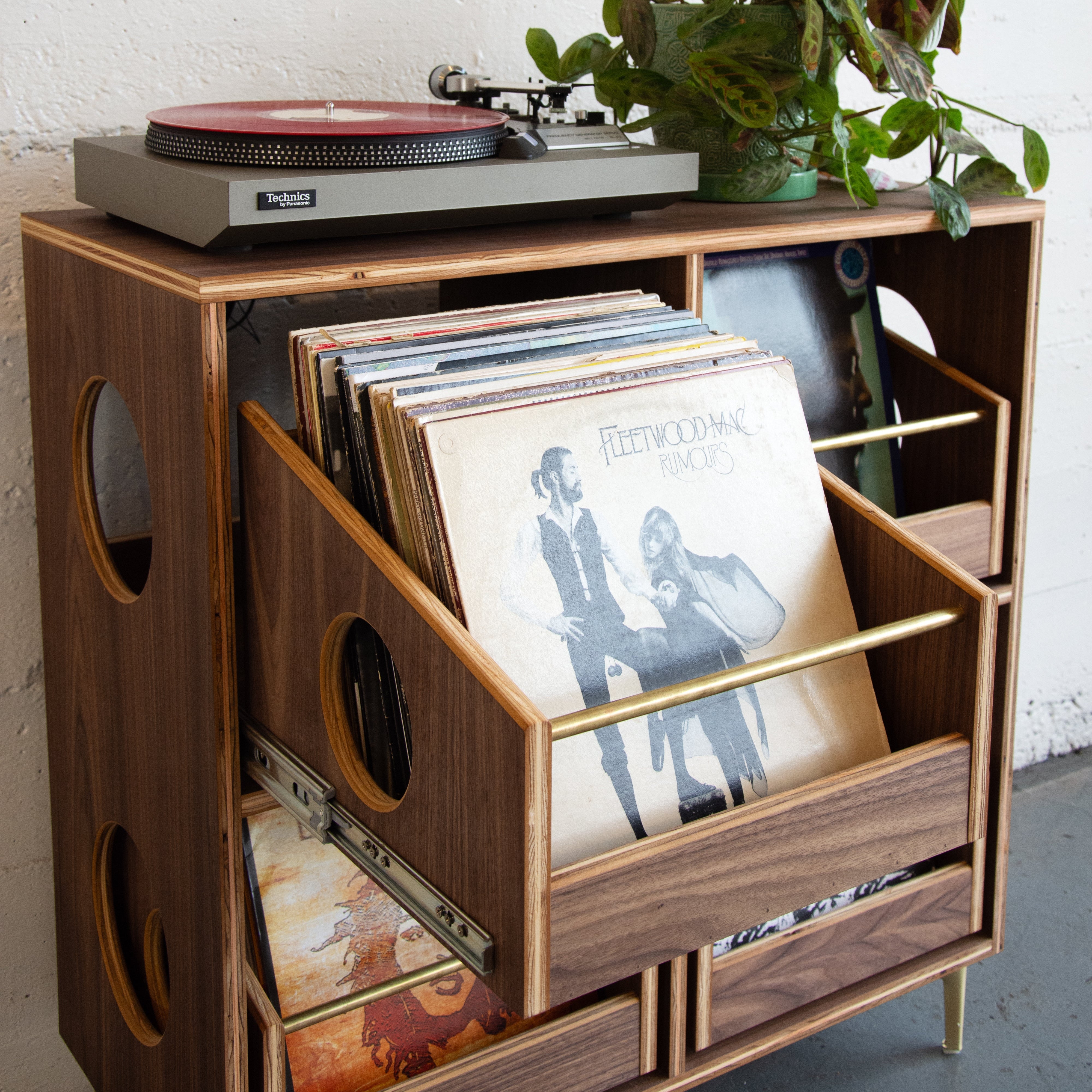 Wooden record player stand with vinyl records and a turntable.