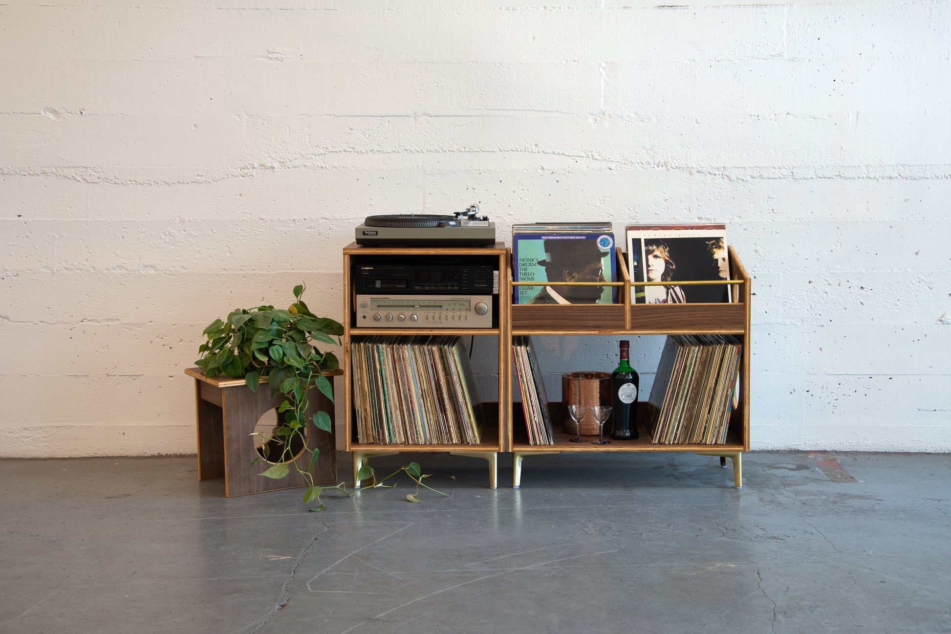 Wooden record player and vinyl collection against a white brick wall.