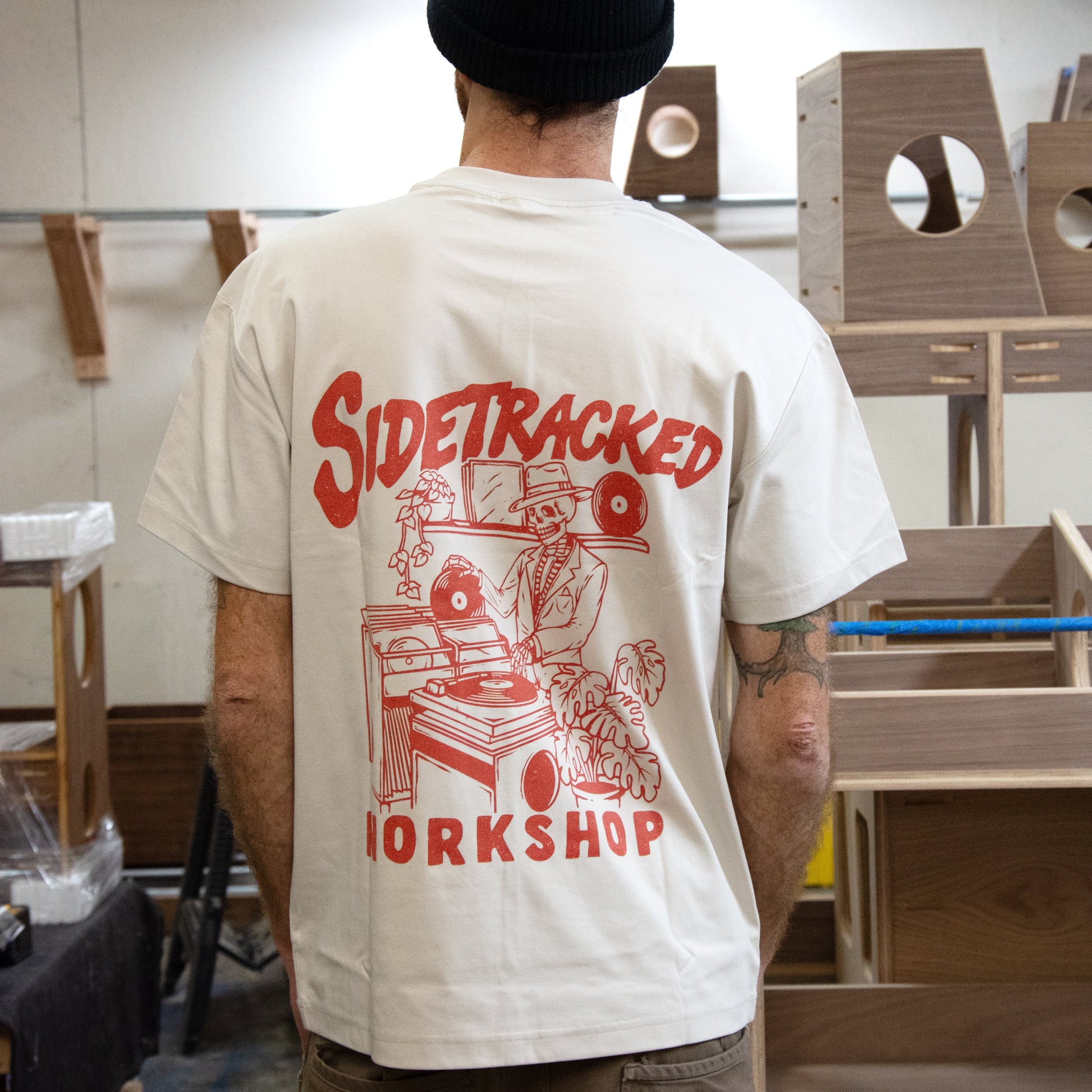 Person wearing a 'Sidetracked Workshop' t-shirt in a workshop setting