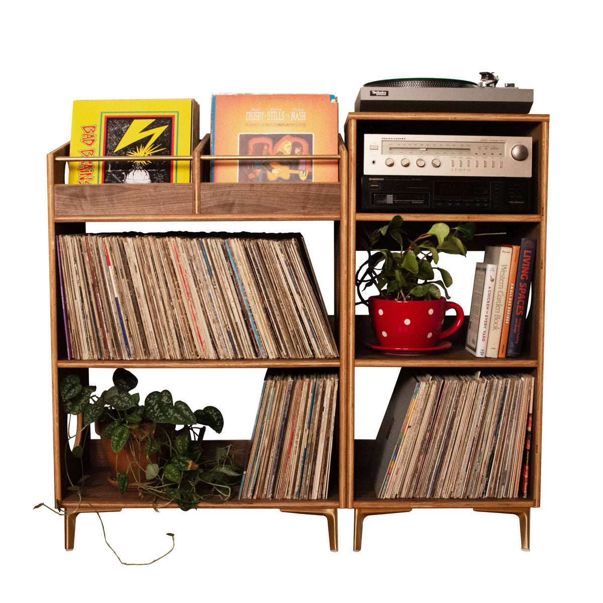 A mid-century modern wooden record shelf and media console with two matching cabinet units, styled with vinyl records, a turntable, books, and potted plants, isolated on a white background.
