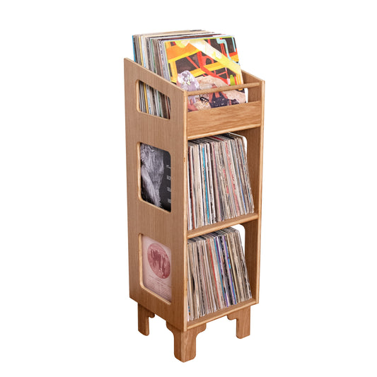 A light natural wood record rack stand holding multiple vinyl records, isolated on a solid white background.