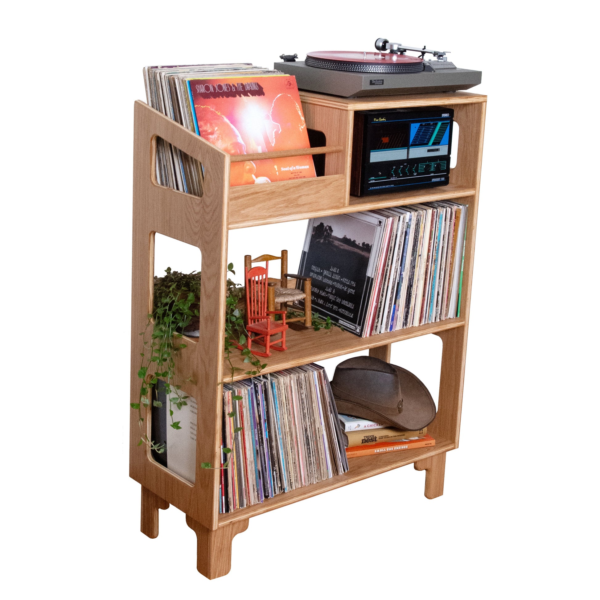 A light natural wood record player shelf unit with three tiers, styled with vinyl records, a turntable, and small decorative plants, isolated on a white background.