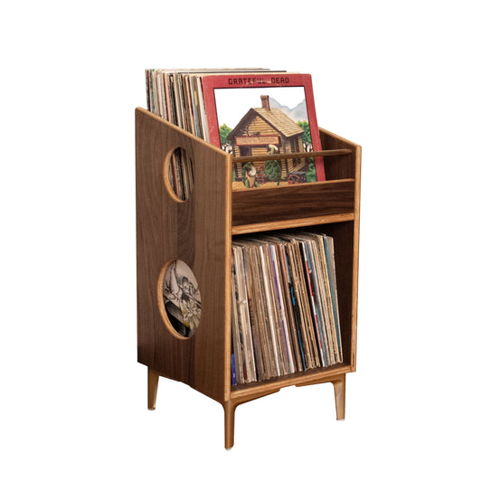 A mid-century modern wooden record store and vinyl record rack, shown holding several vinyl records and a record sleeve, isolated on a white background.