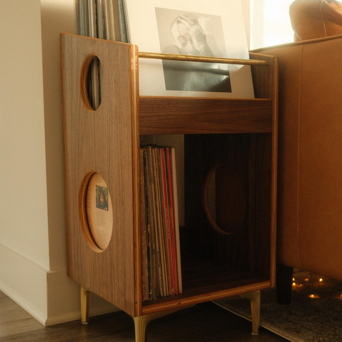 Wooden record player cabinet with vinyl records inside, placed against a wall.
